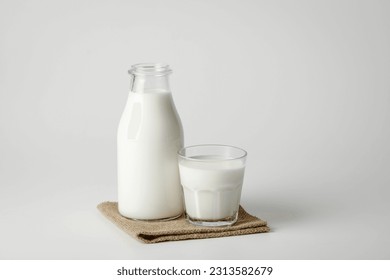 A glass and bottle of milk of milk on brown napkin and a white background - Powered by Shutterstock