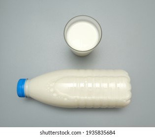 glass and bottle with milk on gray background