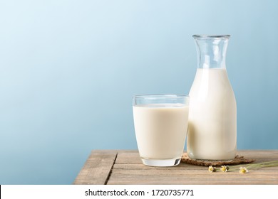 A glass and bottle of milk on wooden table with light blue background. - Shutterstock ID 1720735771