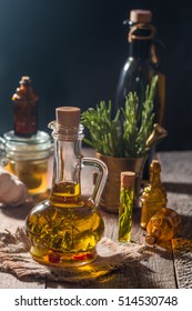 Glass bottle of olive oil with herbs on dark background