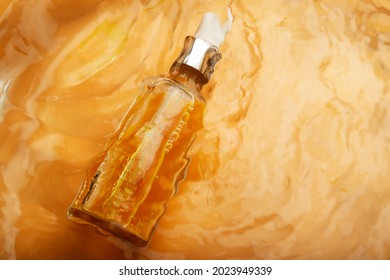 Glass Bottle With Orange Cosmetic Oil Floating In Moving Water