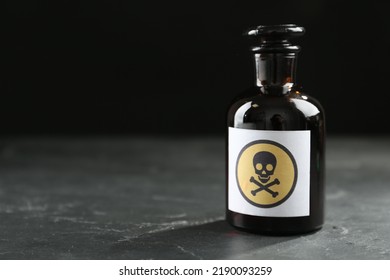 Glass Bottle Of Poison With Warning Sign On Black Table. Space For Text