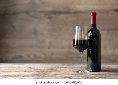 Glass And Bottle Of Red Wine On Wooden Table. Space For Text