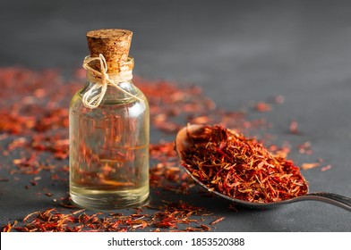 Glass bottle of saffron essential oil with dried saffron spice on rustic background, spice or herb oil concept, alternative medicine (Crocus sativus)