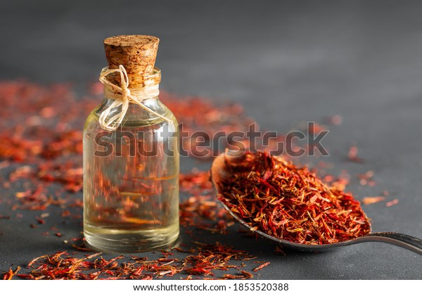 Glass bottle of saffron essential oil with dried\
saffron spice on rustic background, spice or herb oil concept,\
alternative medicine (Crocus\
sativus)