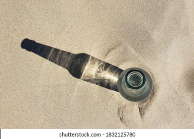 Glass Bottle With Shadow On Clean Beach Sand. Copy Space