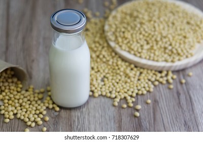 Glass Bottle Of Soy Milk / Soya Milk With Spilled Container Of Soy Beans On Wooden Background.