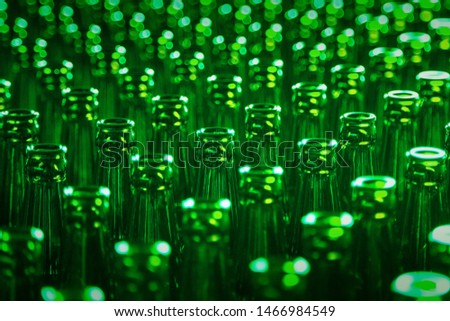 Glass bottle texture pattern. Glass bottle at factory for production of glass containers. Green Beer Bottle Neck. Many of transparent green glass bottle into row, close up.