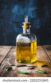 A Glass Bottle With Virgin Olive Oil On A Rustic Table, With Blue Background And Copy Space