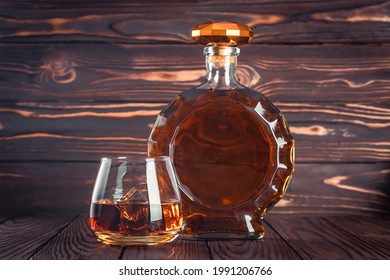 Glass And Bottle Of Whiskey. Decanter With Cognac On A Dark Brown Wooden Table. Brandy, Bourbon. Strong Alcohol Drink. Rum, Scotch. Still Life In A Rustic Style.