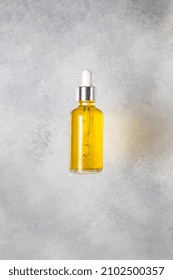 Glass Bottle With Yellow Face Oil On A Gray Background. Flatlay Body Care Serum