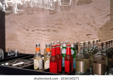 Glass bottles with assorted drinks arranged on a black bar shelf