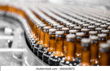 Glass bottles of beer on dark background with sun light. Concept brewery plant production line.