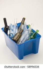 Glass Bottles In A Blue Recycling Bin. White Background.