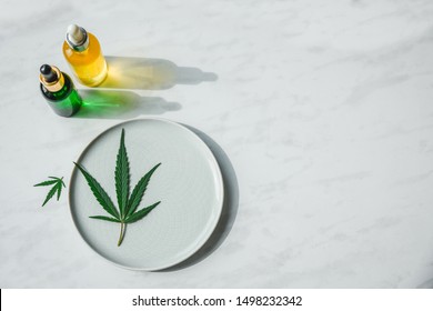 Glass Bottles With CBD Oil, THC Tincture And Hemp Leaves On A Marble Background. Copy Space, Mockup. Cosmetics CBD Oil.