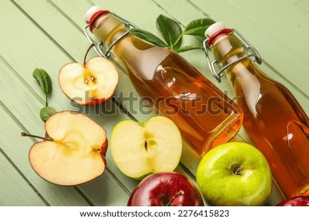Glass bottles of fresh apple cider vinegar and fruits on green wooden background Stok fotoğraf © 