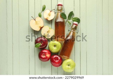 Glass bottles of fresh apple cider vinegar and fruits on green wooden background Stok fotoğraf © 