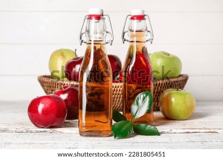 Glass bottles of fresh apple cider vinegar and basket with fruits on white wooden table Stok fotoğraf © 