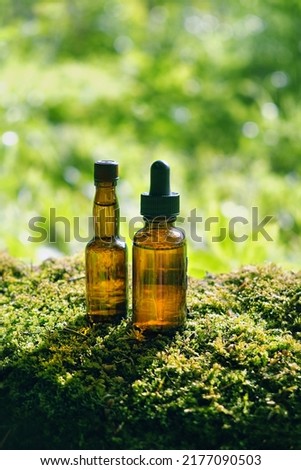 Glass Bottles of herbal essence extract on moss close up, abstract natural background. eco friendly care organic product. beauty treatment, Spa concept. Cosmetic products advertising backdrop design.