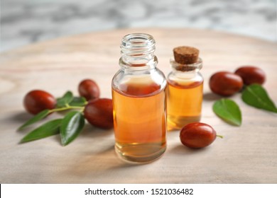Glass bottles with jojoba oil and seeds on light table