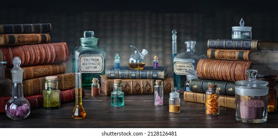 Glass bottles, old books on table of a scientist. Medicine, chemistry, pharmacy, apothecary, alchemy history background. Translation from labels-eyewash astringent, morphine hydrochloride and almonds.