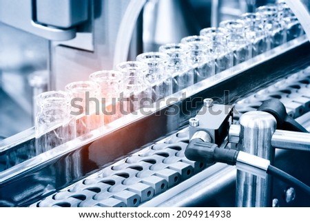 Glass bottles in production in the tray of an automatic liquid dispenser; a line for filling medicines against bacteria and viruses; antibiotics and vaccines.