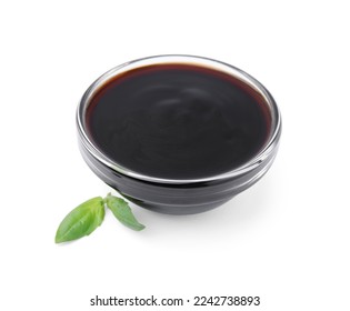 Glass bowl with balsamic glaze and basil leaves on white background