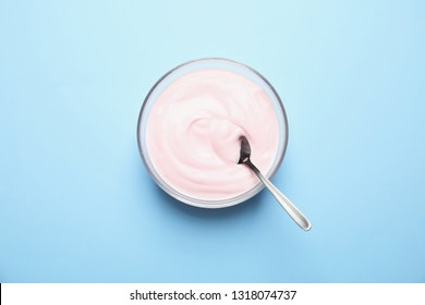 Glass Bowl With Creamy Yogurt And Spoon On Color Background, Top View