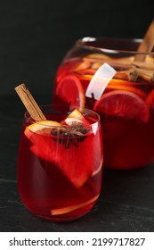 Glass And Bowl Of Delicious Aromatic Punch Drink On Black Table