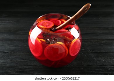 Glass Bowl Of Delicious Aromatic Punch Drink And Ladle On Black Wooden Table