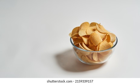 Glass Bowl Full Of Delicious And Appetizing Heap Of Potato Chips. Unhealthy Eating And Junk Food. Crispy Snack For Takeaway And Leisure. Isolated On White Background. Studio Shoot. Copy Space