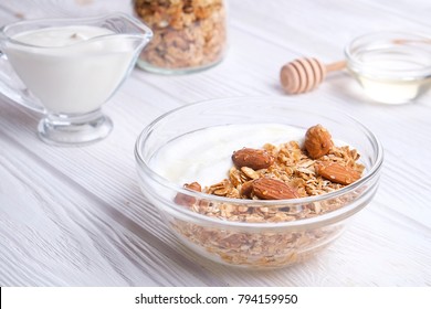 Glass Bowl With Greek Yogurt And Mixed Nuts. Healthy Sports Vegetarian Protein Rich Diet, Homemade Granola Breakfast With Milk, Honey, Almond, Cashew, Hazelnut, Rolled Oats. Top Front View, Background