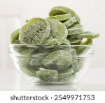 Glass bowl with sliced freeze-dried kiwi fruits on white background. Concept of healthy and diet food..