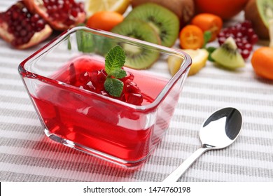 Glass bowl of tasty jelly and spoon on table