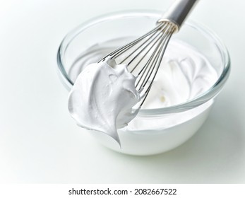 glass bowl of whipped egg whites cream on white kitchen table background