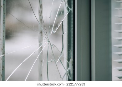 Glass broken by hooligans in metal  plastic window  close  up 