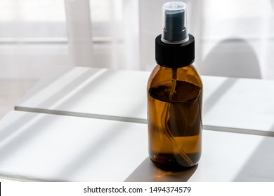 Glass Brown Spray Bottle With Organic Cosmetics On White Table. Direct Light. Beauty Blogging Minimalism Concept