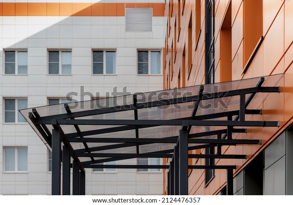 Glass canopy to protect from\
precipitation at the entrance to a modern office\
building