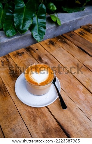 glass of cappuccino on wooden background with beautiful latte art of heart shape. love concept. top view.