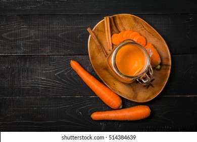 Glass Of Carrot Juice And Carrots On Black Wooden Background, Top View