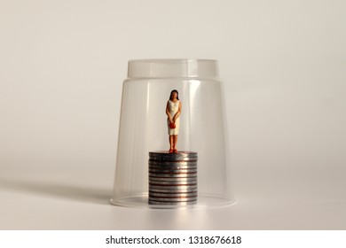 A Glass Ceiling Concept. Miniature Women And Coins.