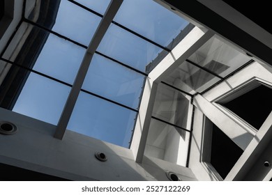 A glass ceiling with geometric patterns reflecting clear blue sky - Powered by Shutterstock