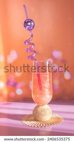 A Glass of Champagne with a Disco Ball Mirror Ball Straw on A Celebratory Bokeh Background in Orange