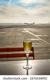 Glass Of Champagne On A Table In An Airport Business Lounge With An Aircraft Taking Off Burred In The Background