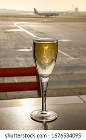 Glass Of Champagne On A Table In An Airport Business Lounge With An Aircraft Burred In The Background