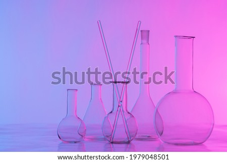 Glass chemical dishes on a lilac background. Flasks and glass sticks on the table in the laboratory. Equipment of the chemical laboratory. Conducting experiments.