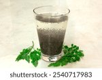 A glass of chia seeds soaked overnight in water, with fresh moringa leaves beside it for a natural, vibrant touch. This nutrient-rich, hydrating superfood drink is perfect for wellness and health