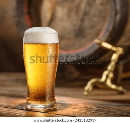 Glass of chilled beer and wooden beer cask on the background. 