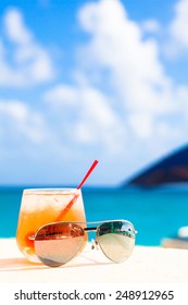 Glass Of Chilled Cocktail Rum Punch And Sunglasses On Table Near The Beach