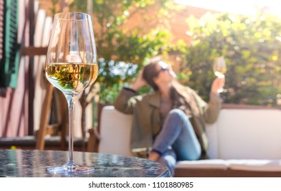 glass of chilled white wine on table over young woman and Tuscany backgound